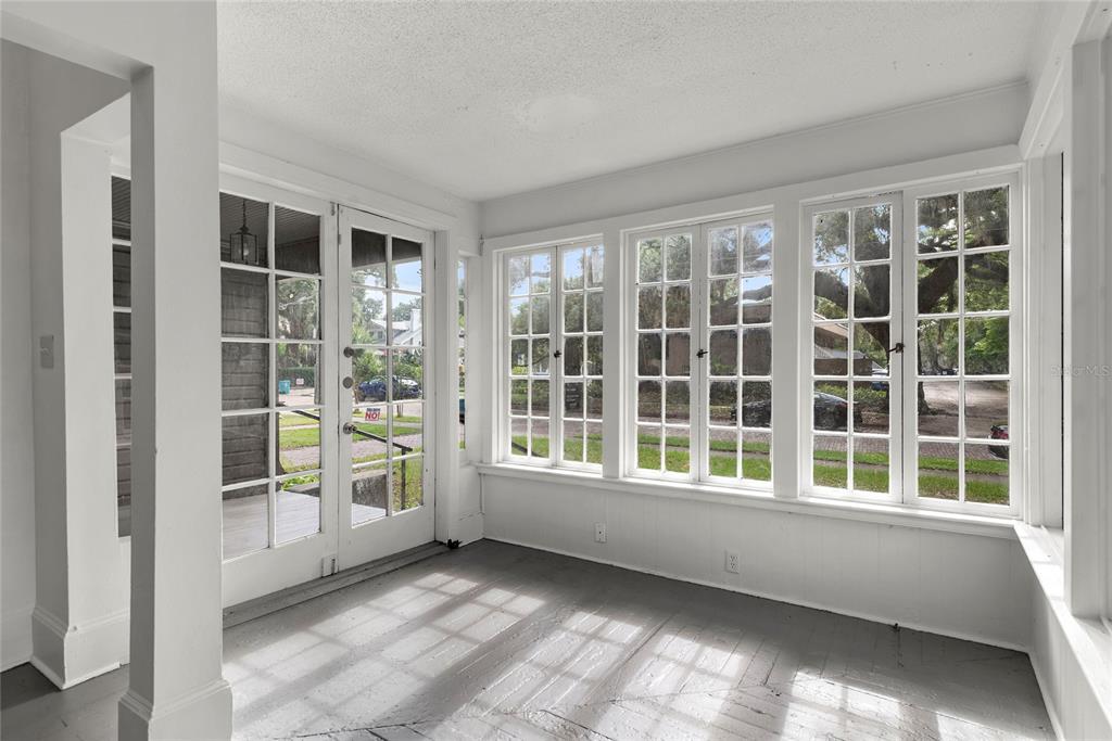 A sunroom with white walls, gray painted floors, and multiple windows overlooking a residential street — 522 S OSCEOLA AVENUE, ORLANDO, FL