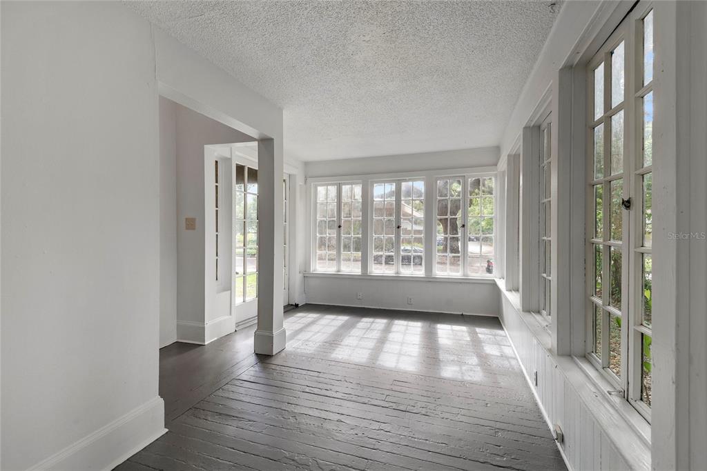 A sunroom with dark wood floors, white walls, and multiple windows overlooking a street — 522 S OSCEOLA AVENUE, ORLANDO, FL