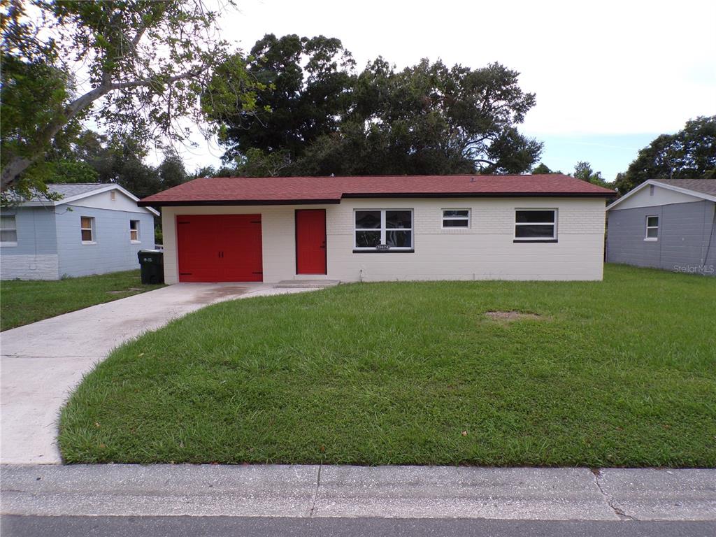 A single-story house with a red roof, red garage door, and red front door — 13674 120TH LANE, SEMINOLE, FL