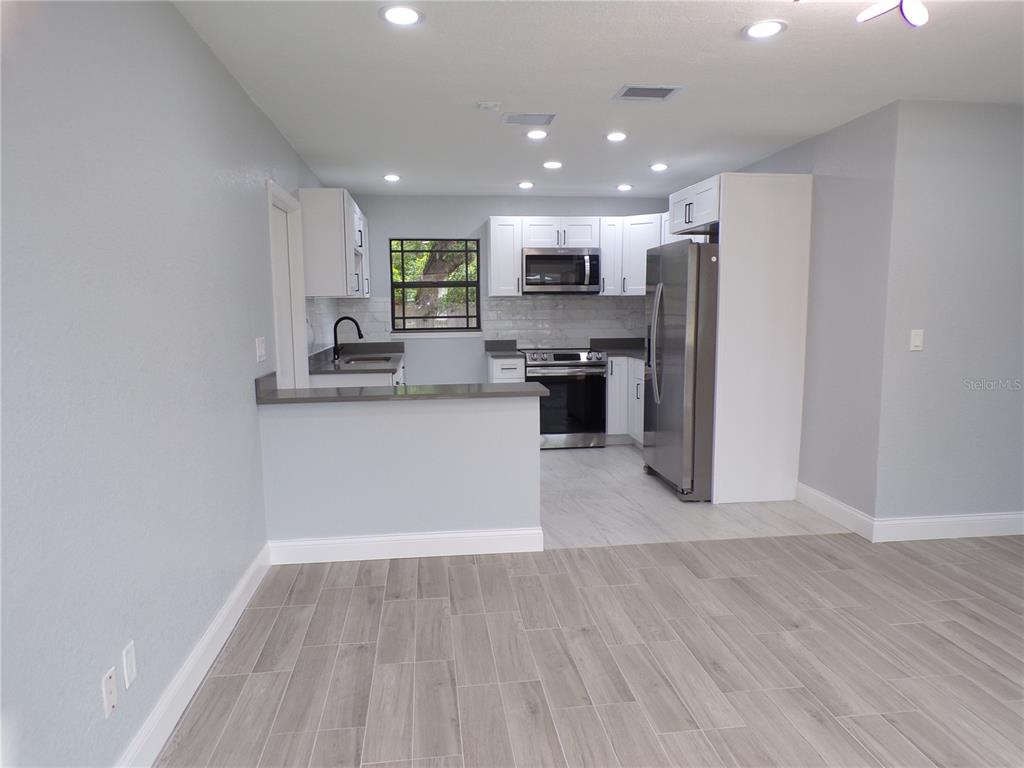 A kitchen with white cabinets, stainless steel appliances, and gray wood-look tile flooring — 13674 120TH LANE, SEMINOLE, FL