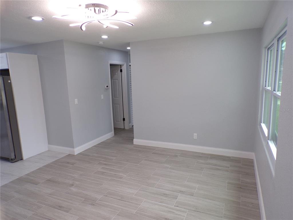 A room with light gray walls, wood-look tile flooring, a modern light fixture, and windows — 13674 120TH LANE, SEMINOLE, FL