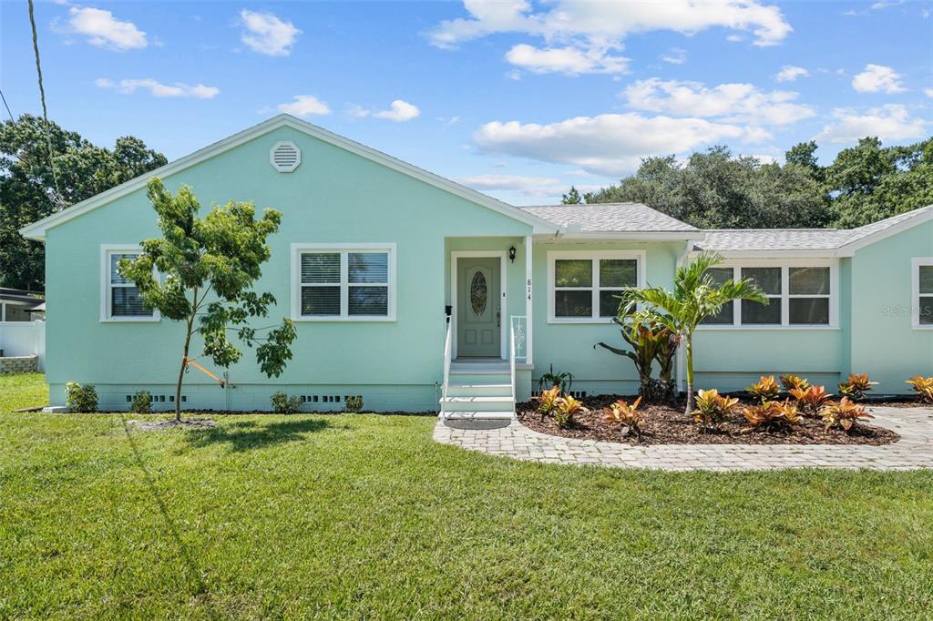 A light green single-story house features a front door, white-framed windows, and a landscaped yard — 814 W INDIANA AVENUE, TAMPA, FL