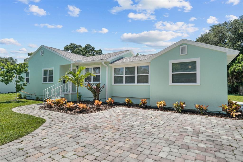 A light green ranch-style house features a paver driveway and a landscaped front garden — 814 W INDIANA AVENUE, TAMPA, FL