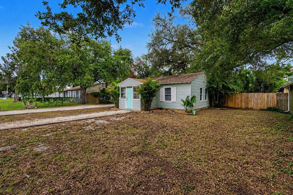 A light blue single-story house with a gravel driveway sits on a grassy lot — 3208 W HARTNETT AVENUE, TAMPA, FL