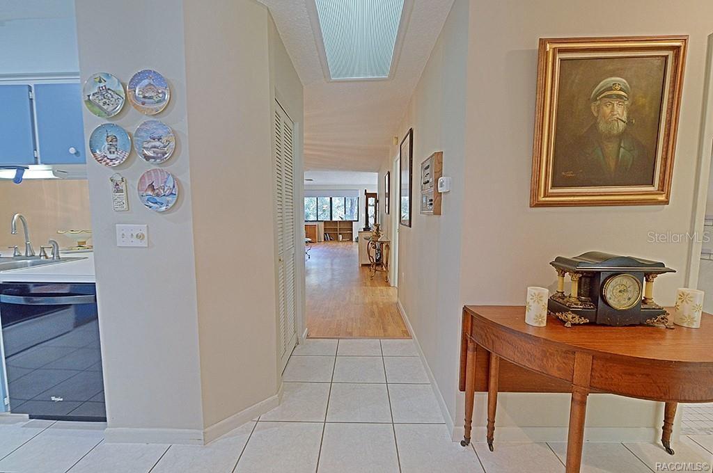 A hallway with tile flooring leads from a kitchen area toward a living space — 3371 S BELGRAVE DRIVE, INVERNESS, FL