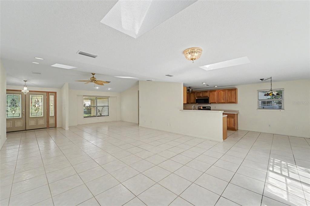A spacious, tiled living room features a vaulted ceiling with multiple skylights and double doors — 2057 BRENT PLACE, PALM HARBOR, FL