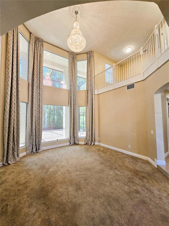 A formal living room features high ceilings, floor-to-ceiling curtains, and ornate, light-colored furniture — 3405 HEIRLOOM ROSE PLACE, OVIEDO, FL