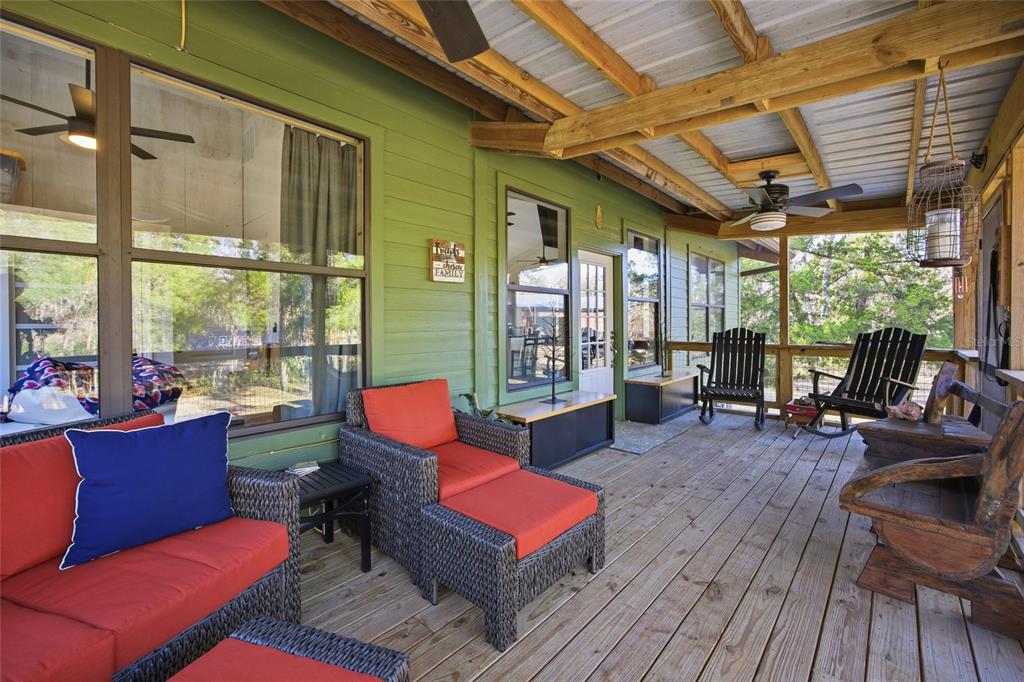 A screened-in wooden porch features a rocking chair, a rustic bench, and outdoor views — Track 79 CLAYTON ROAD, CEDAR KEY, FL