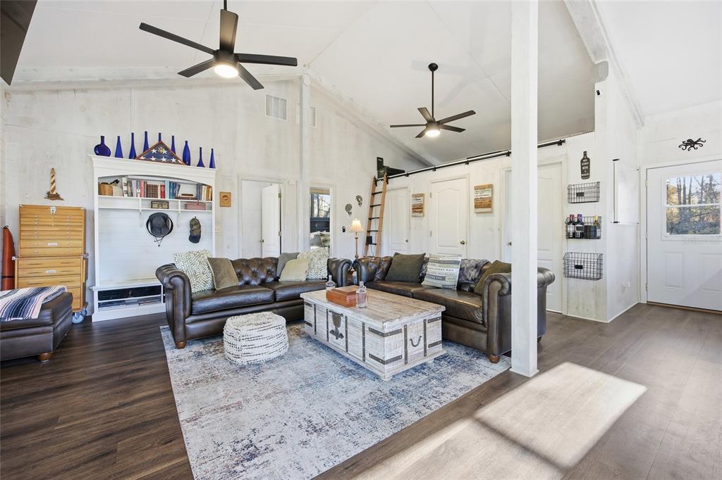A covered wooden porch features wicker furniture with orange cushions and a green exterior wall — Track 79 CLAYTON ROAD, CEDAR KEY, FL