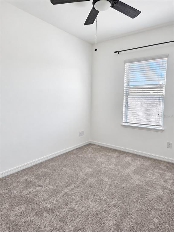 An empty bedroom features white walls, gray carpeting, a ceiling fan, and a window with blinds — 11649 WATER RUN ALLEY, WINDERMERE, FL
