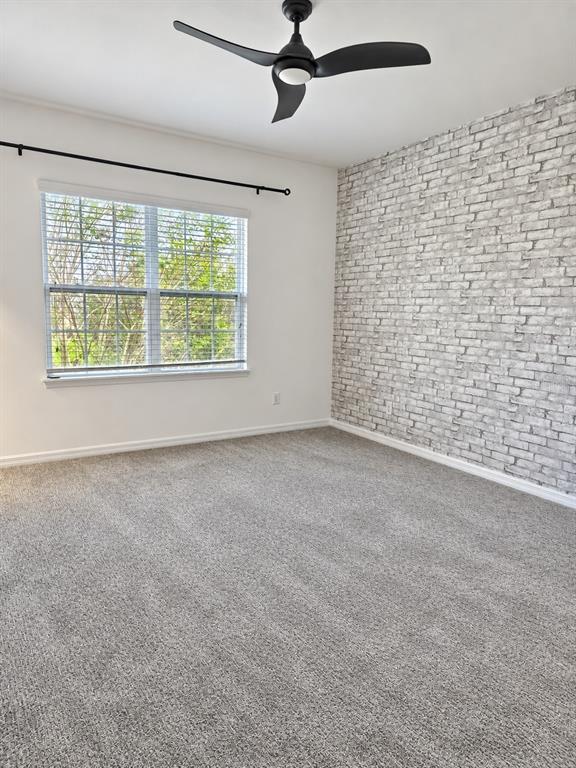 An empty bedroom features gray carpet, a faux brick accent wall, and a ceiling fan — 11649 WATER RUN ALLEY, WINDERMERE, FL