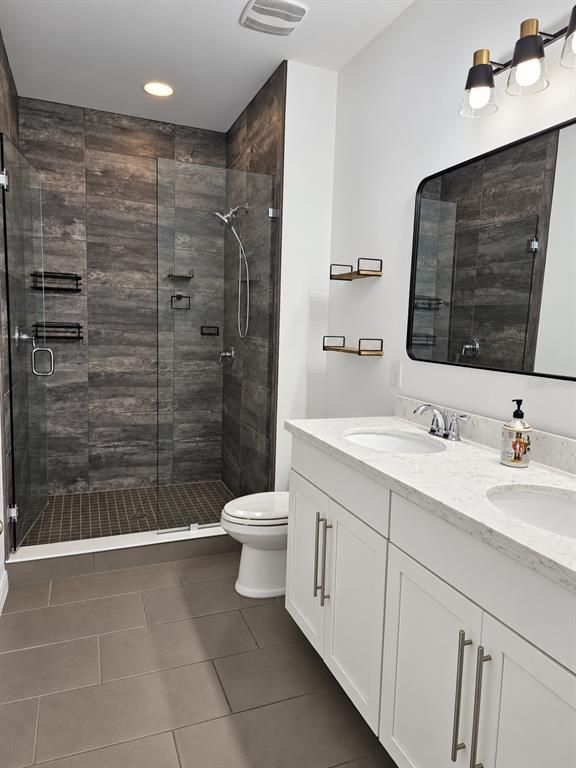 A modern bathroom features a glass-enclosed walk-in shower, double vanity, and dark wood-look tile walls — 11649 WATER RUN ALLEY, WINDERMERE, FL