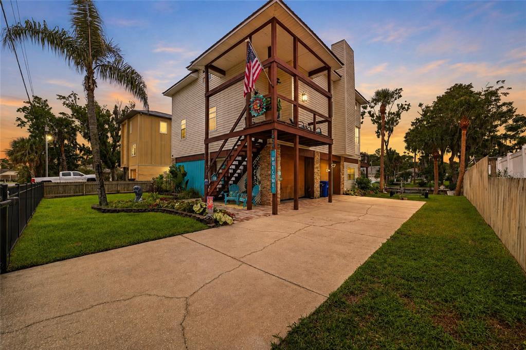 A two-story elevated house with a concrete driveway, a wooden staircase, and a front porch — 1424 SE 5TH AVENUE, CRYSTAL RIVER, FL