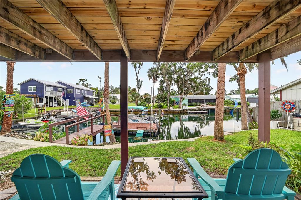A covered patio with two chairs overlooks a canal with boat docks and residential houses — 1424 SE 5TH AVENUE, CRYSTAL RIVER, FL