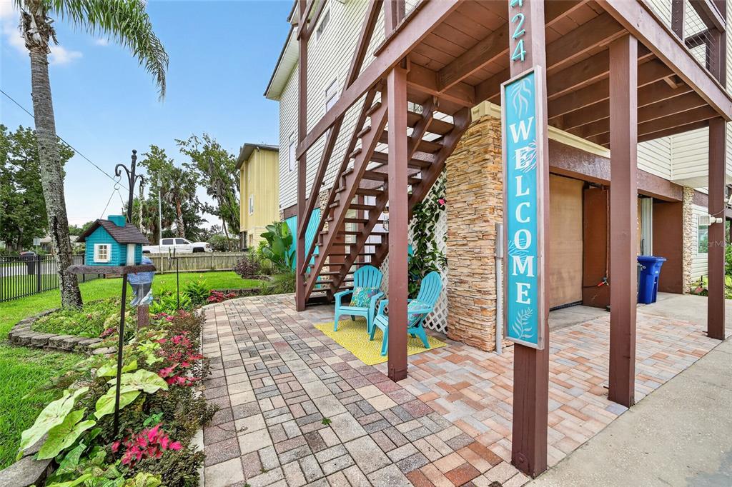 A paved patio area features two blue chairs, a welcome sign, and wooden stairs — 1424 SE 5TH AVENUE, CRYSTAL RIVER, FL