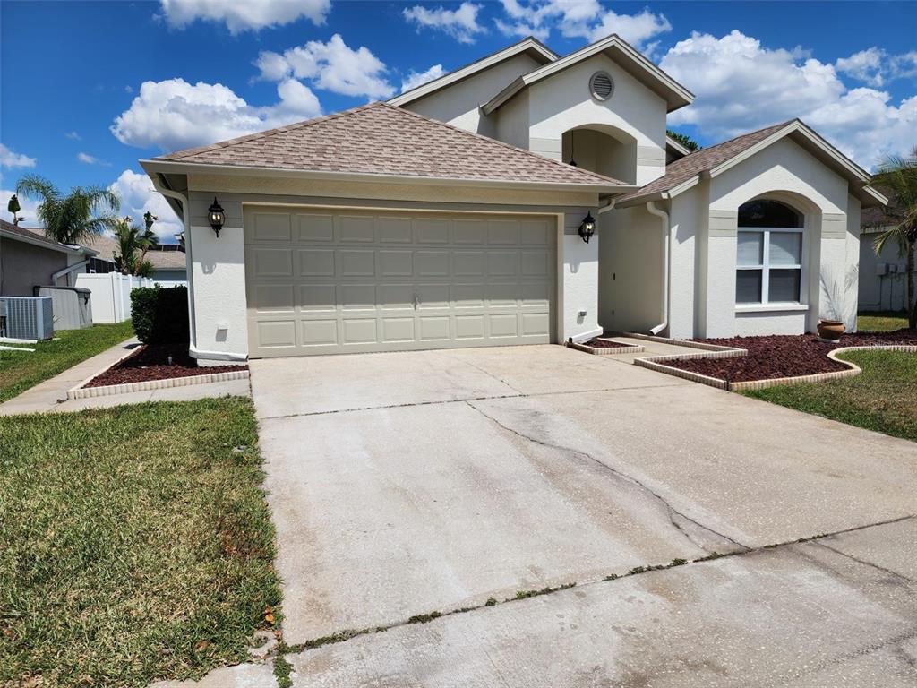 A beige stucco house with a two-car garage and a concrete driveway under a sky — 29545 MORWEN PLACE, WESLEY CHAPEL, FL