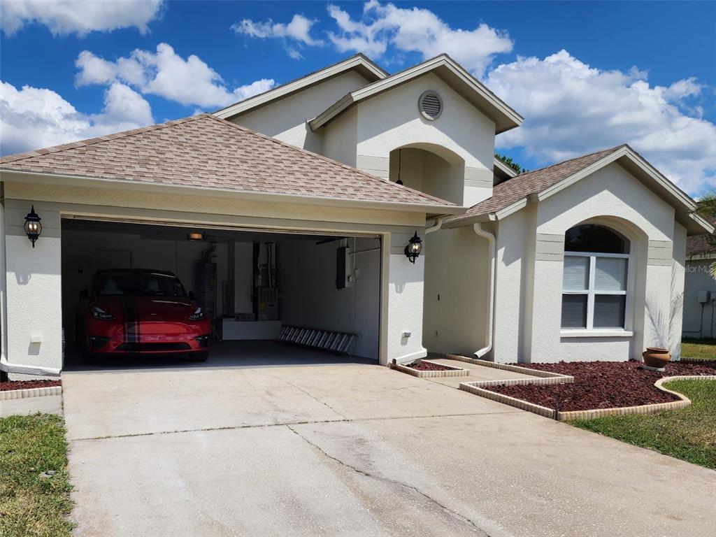 A single-story house with a two-car garage, a red car, and a front entryway — 29545 MORWEN PLACE, WESLEY CHAPEL, FL
