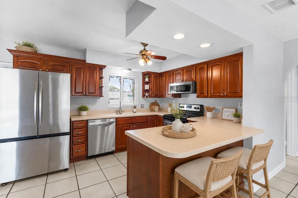 A kitchen with wood cabinets, stainless steel appliances, and a peninsula counter on tile flooring — 605 S FLORIDA AVENUE, TARPON SPRINGS, FL