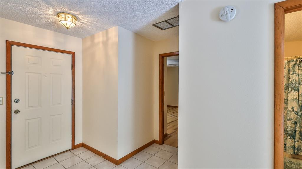 An entryway with tiled floors, a white front door, and a doorway leading to another room — 3103 JUNIPER DRIVE, EDGEWATER, FL