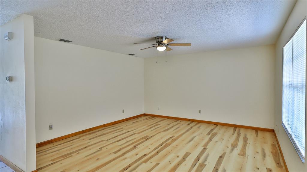 An empty room features light-colored wood-look flooring, white walls, and a ceiling fan — 3103 JUNIPER DRIVE, EDGEWATER, FL