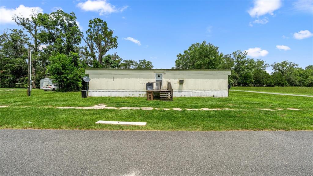 A single-story mobile home sits on a grassy lot with a small wooden porch — 5383 ORANGE STREET, HAMPTON, FL