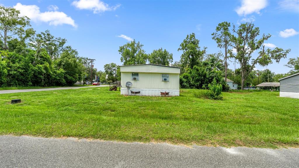 A single-story mobile home sits on a grassy lot under a blue sky — 5383 ORANGE STREET, HAMPTON, FL