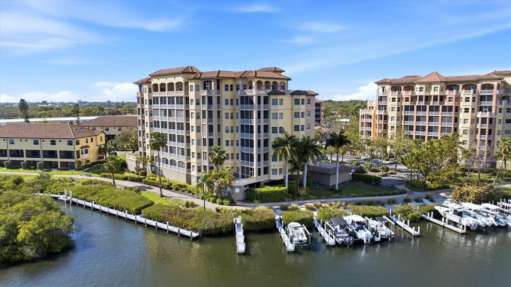 An aerial view shows two large apartment buildings situated along a canal with boat docks — 5531 CANNES CIRCLE UNIT 603, SARASOTA, FL