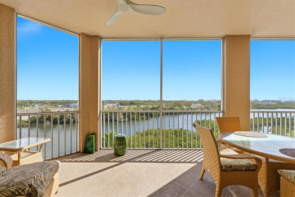 A screened-in balcony features wicker furniture, a ceiling fan, and views of a river — 5531 CANNES CIRCLE UNIT 603, SARASOTA, FL