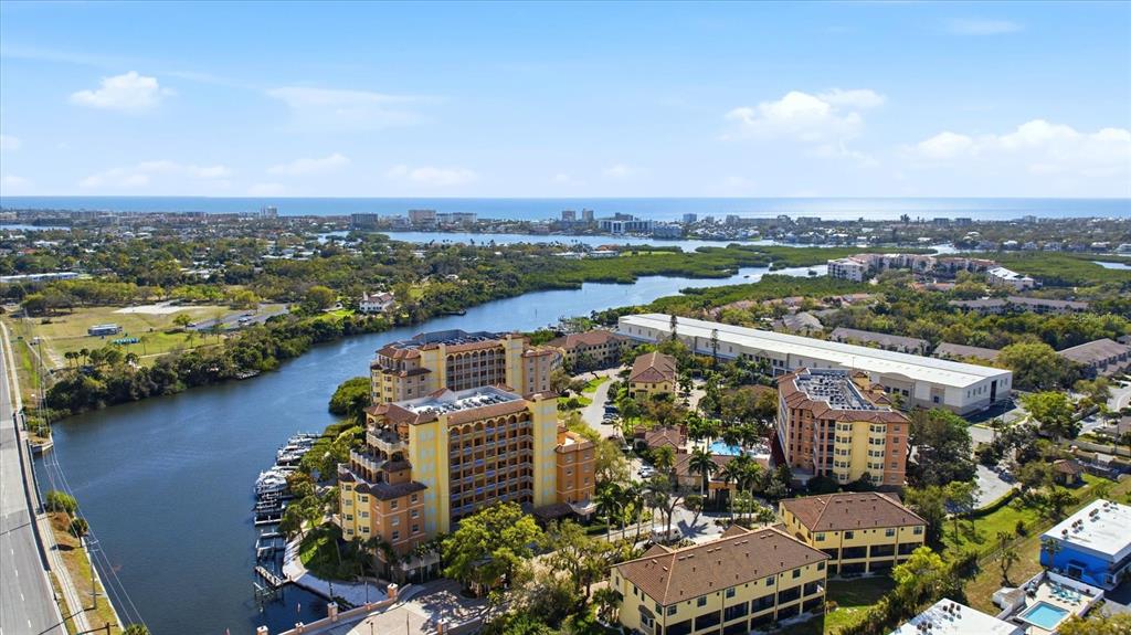 An aerial view shows a waterfront resort complex with multiple buildings, a pool, and boats — 5531 CANNES CIRCLE UNIT 603, SARASOTA, FL