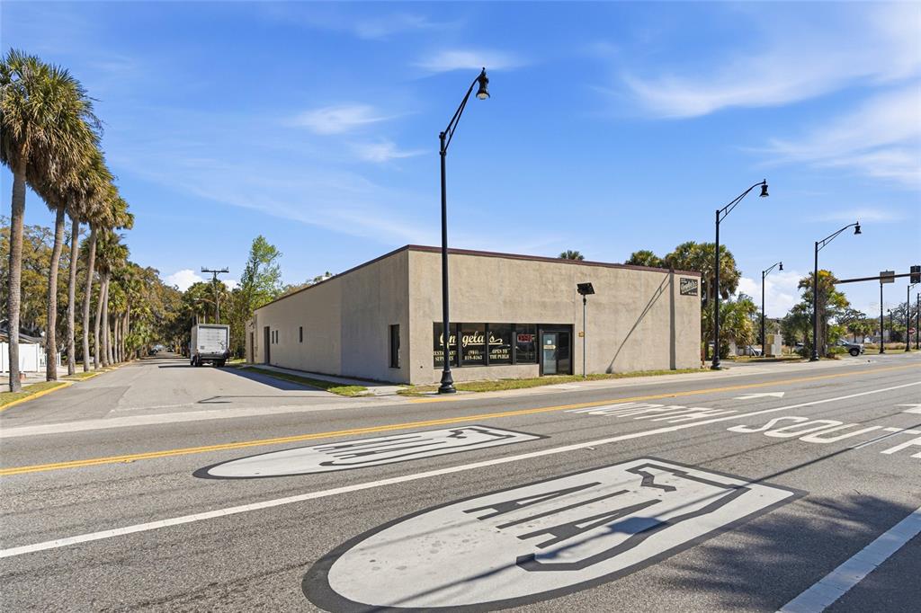 A commercial building stands at a street corner with palm trees along the side road — 185 SAN MARCO AVENUE, ST AUGUSTINE, FL