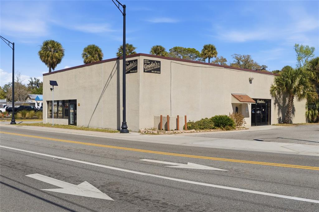 A single-story commercial building with a tan stucco exterior and palm trees in the background — 185 SAN MARCO AVENUE, ST AUGUSTINE, FL