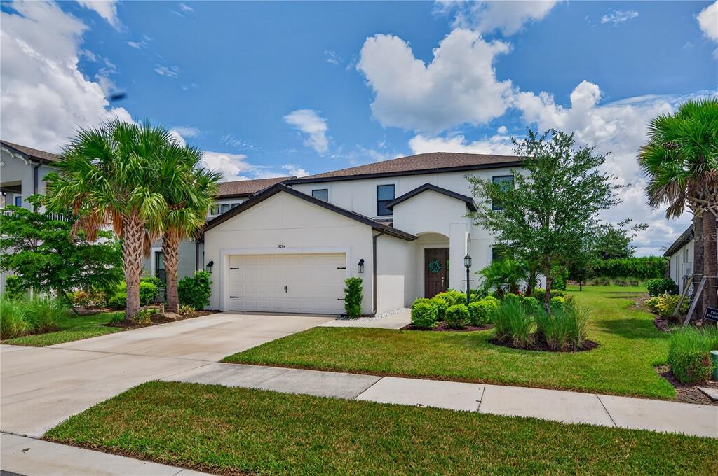 A two-story house with a white stucco exterior, a two-car garage, and palm trees — 9284 TEQUILA SUNRISE DRIVE, SARASOTA, FL