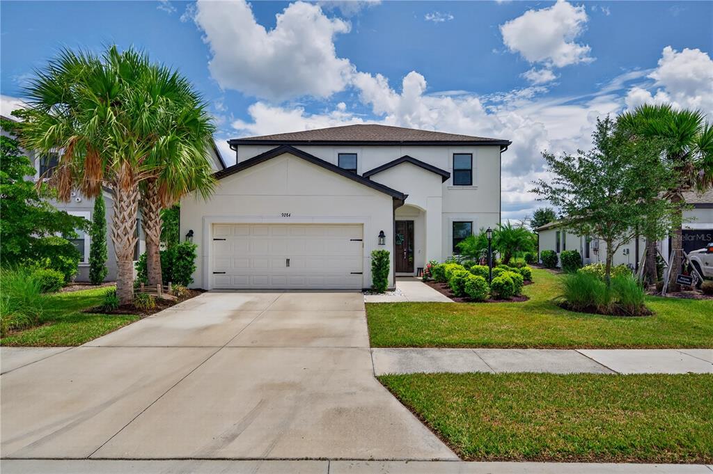 A two-story suburban house with a white stucco exterior, a two-car garage, and palm trees — 9284 TEQUILA SUNRISE DRIVE, SARASOTA, FL