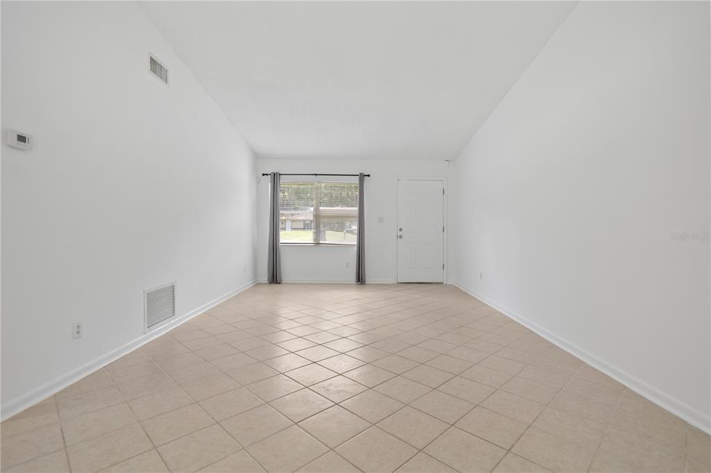 An empty room with white walls, tile flooring, a window with curtains, and a door — 1923 BONNEVILLE DRIVE, ORLANDO, FL