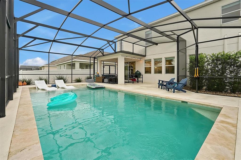 A screened-in patio features a rectangular swimming pool with lounge chairs and a covered area — 10264 LOVE STORY STREET, WINTER GARDEN, FL