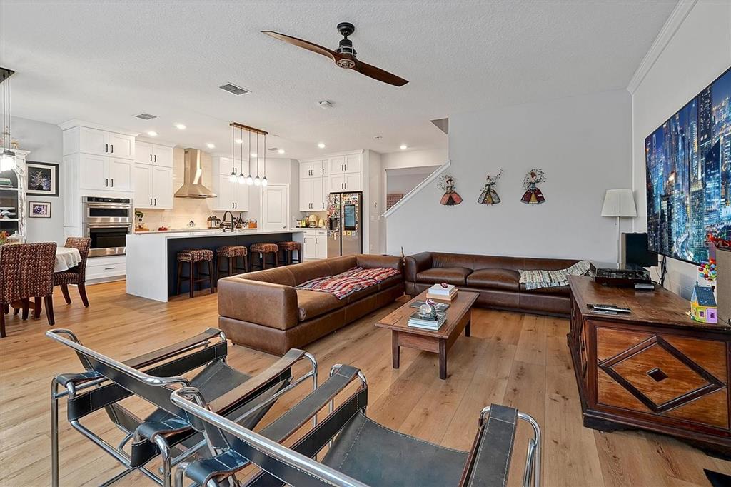 An open-concept living area features light wood flooring, a ceiling fan, and sliding glass doors — 10264 LOVE STORY STREET, WINTER GARDEN, FL