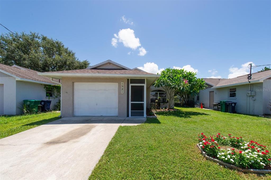 A single-story house with a white garage door, a screened entryway, and a front lawn — 1521 13TH STREET W, PALMETTO, FL