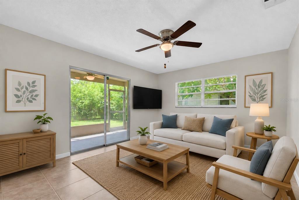 A living room features a beige sofa, wooden coffee table, ceiling fan, and sliding glass doors — 1521 13TH STREET W, PALMETTO, FL