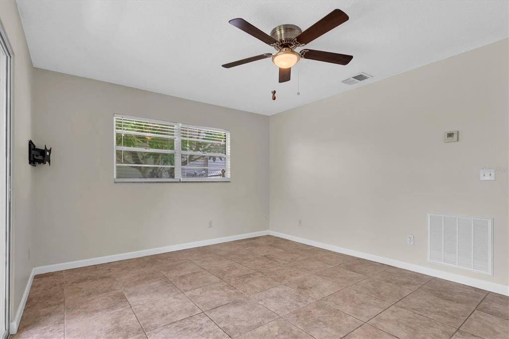 An empty room with beige walls, tile flooring, a ceiling fan, and a window — 1521 13TH STREET W, PALMETTO, FL