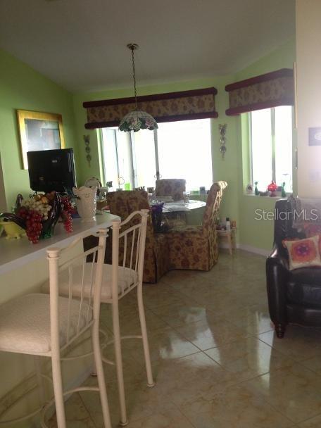 A dining area with a breakfast bar, light green walls, and tile flooring — 8 SUTTON CT, PALM COAST, FL