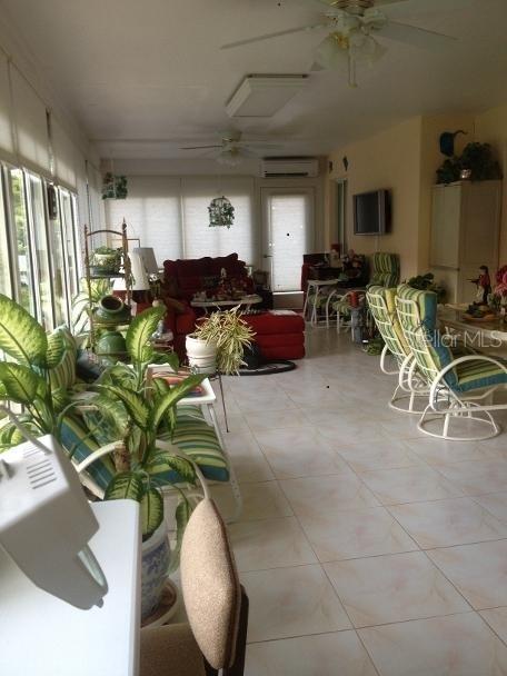 A sunroom features tile flooring, ceiling fans, and a seating area with a red sofa — 8 SUTTON CT, PALM COAST, FL