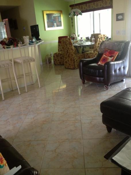 A living room and dining area feature light-colored tile floors and a dark leather armchair — 8 SUTTON CT, PALM COAST, FL