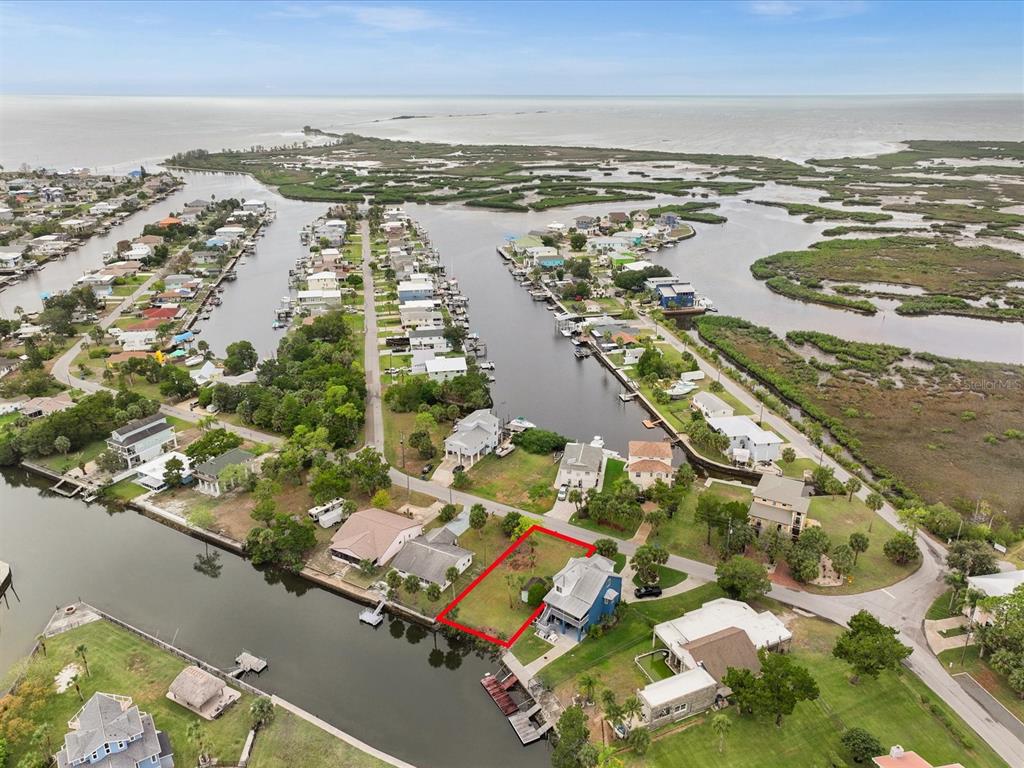 An aerial view shows a waterfront residential lot outlined in red next to a blue house — 3468 MINNOW CREEK DRIVE, HERNANDO BEACH, FL