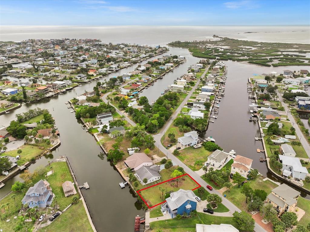 An aerial view shows a vacant waterfront lot outlined in red next to a blue house — 3468 MINNOW CREEK DRIVE, HERNANDO BEACH, FL