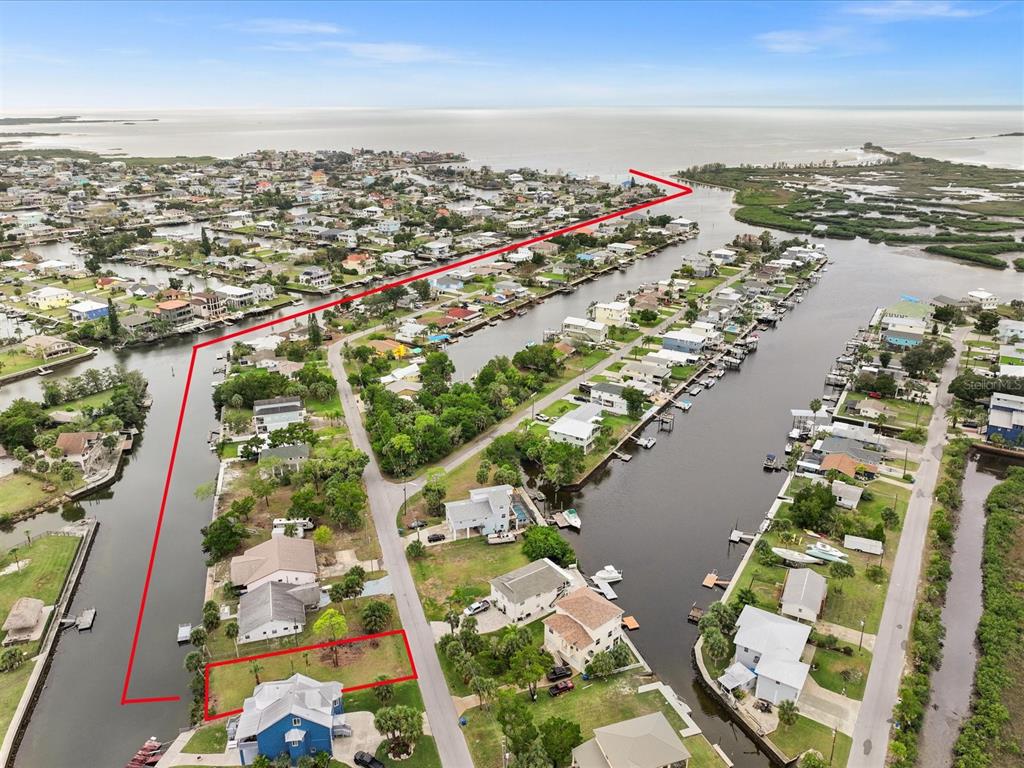 An aerial view shows a waterfront residential lot outlined in red along a canal — 3468 MINNOW CREEK DRIVE, HERNANDO BEACH, FL