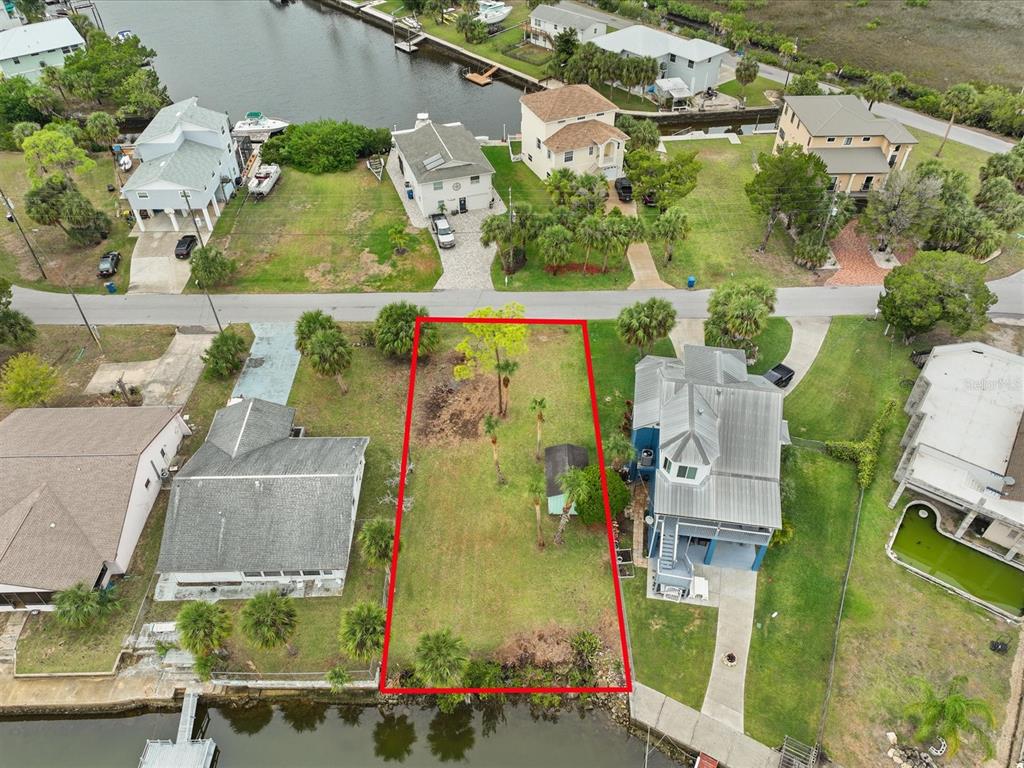 An aerial view shows a vacant waterfront lot outlined in red between two existing houses — 3468 MINNOW CREEK DRIVE, HERNANDO BEACH, FL