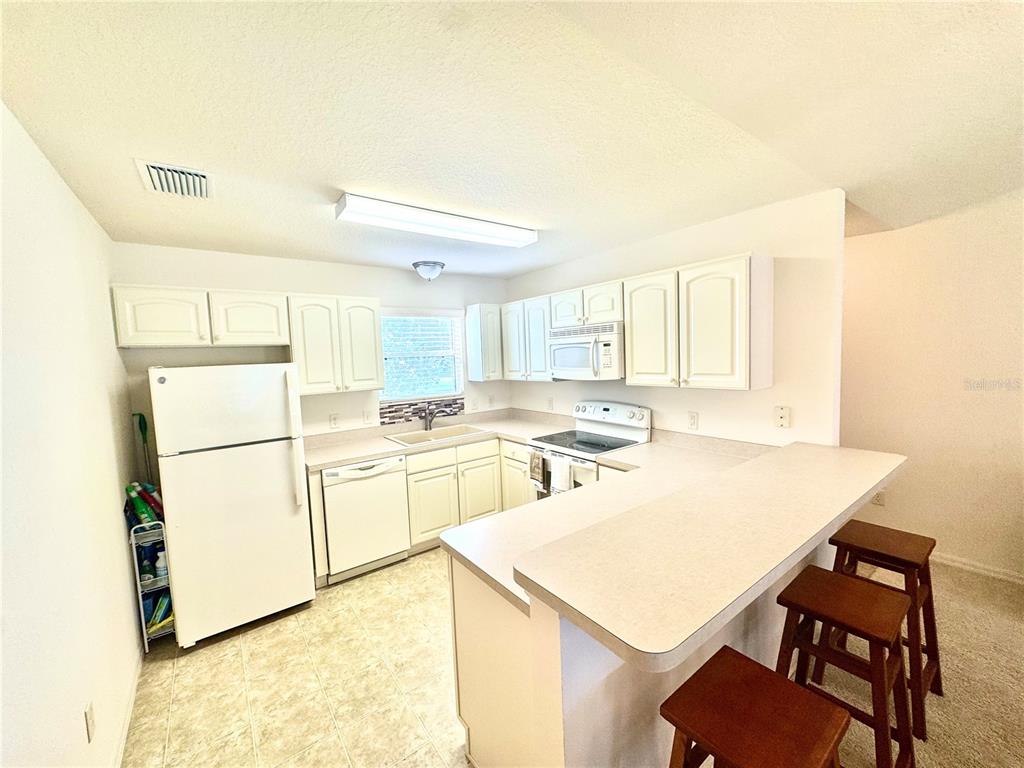 A fenced backyard with a green lawn and a concrete patio area — 892 NASH LOOP, THE VILLAGES, FL