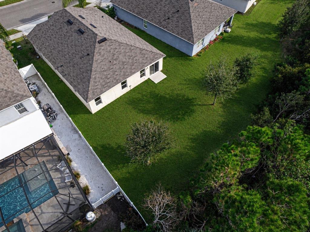 The exterior rear view of a beige stucco house with a lawn and white fence — 2952 GIBRALTAR BOULEVARD, NEW SMYRNA BEACH, FL