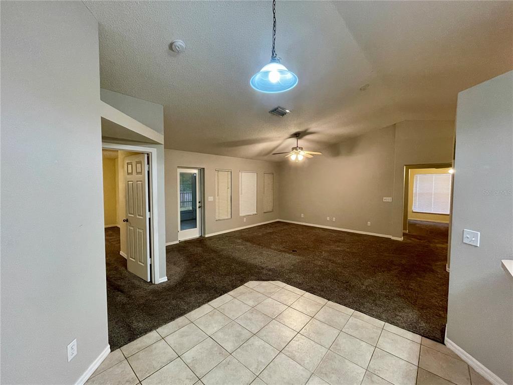 A living room with dark carpet, neutral walls, a ceiling fan, and a tile entryway — 12119 WARWICK CIRCLE, PARRISH, FL