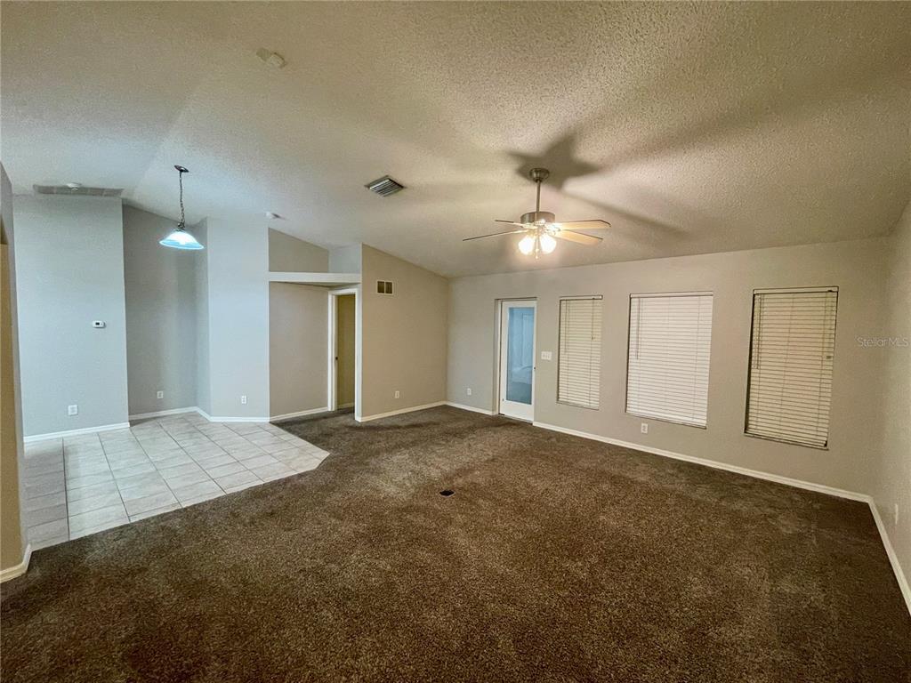 A living room with brown carpeting, a tiled dining area, and a ceiling fan — 12119 WARWICK CIRCLE, PARRISH, FL